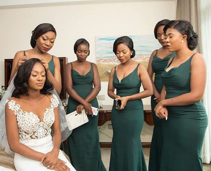 a group of women standing next to each other in front of a bed wearing green dresses