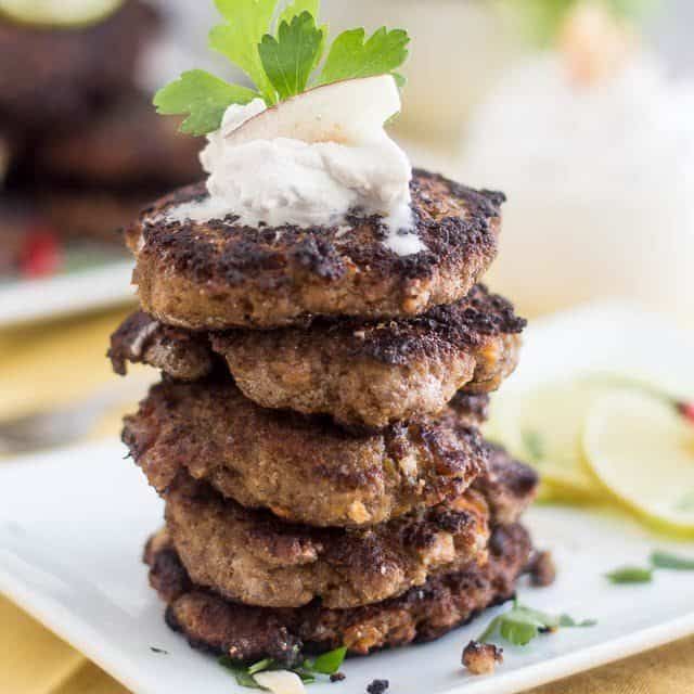 a stack of food sitting on top of a white plate next to a lemon wedge