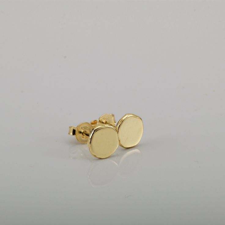 "Shiny round gold 14k stud earrings, simple and perfect for every day's wear.   These gold earrings are handmade of yellow 14k solid gold.  I melted the gold into a ball, and then hammered each ball to its irregular shape. No two are ever identical, and each has a unique and organic look. The edges of the pebbles are rough, while the flat surface has a smooth shiny finish. These are classic \"wear with everything\" gold stud earrings - a perfect gift, or a treat for yourself. Earrings diameter is approx. 7 mm = ~0.27 inch, and they are 1.2 mm thick. 14k solid gold ear backs are included. * The earrings will be packed in a gift box ready to give as a gift, and shipped via Express mail service which usually takes 4-6 business days to arrive. * To see similar earrings in a slightly smaller si 14k Yellow Gold Circle Earrings, Minimalist Round Earrings With Polished Finish, Minimalist Polished Round Earrings, Dainty Round Earrings With Polished Finish, Dainty Yellow Gold Circular Earrings, Simple 14k Gold Earrings, Yellow Gold Simple Earrings, Hypoallergenic Round Earrings In Recycled Gold, Minimalist 14k Gold Round Earrings