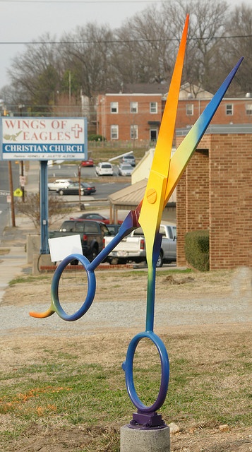 a pair of scissors sitting on top of a cement block in front of a building