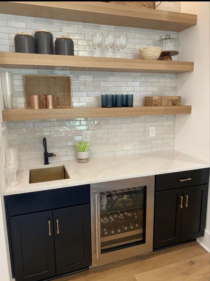 a kitchen with open shelving above the sink and wine glasses on the counter top