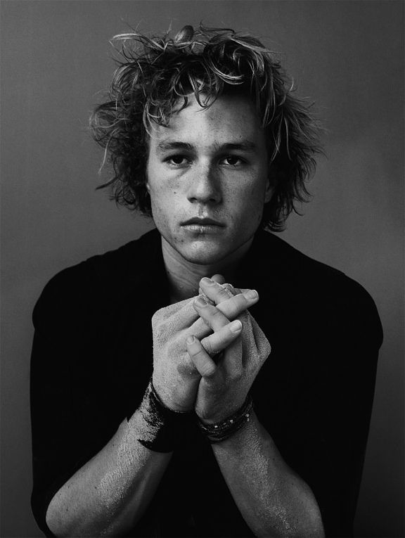 a black and white photo of a young man with his hands folded over his chest