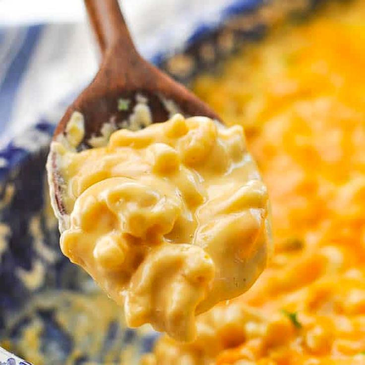 a spoon full of macaroni and cheese being lifted from a casserole dish