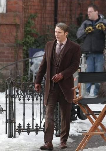 a man in a suit and tie walking on the street with another man behind him