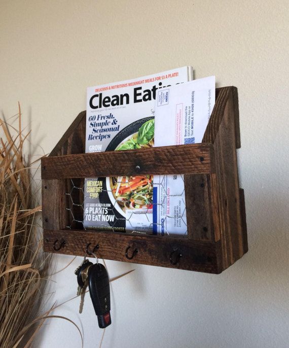 a wooden shelf with magazines and other items hanging on it's wall next to a potted plant