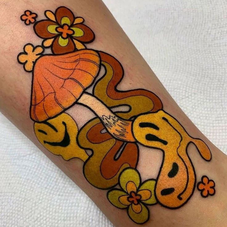 a woman's leg with an orange and yellow tattoo design on her arm,