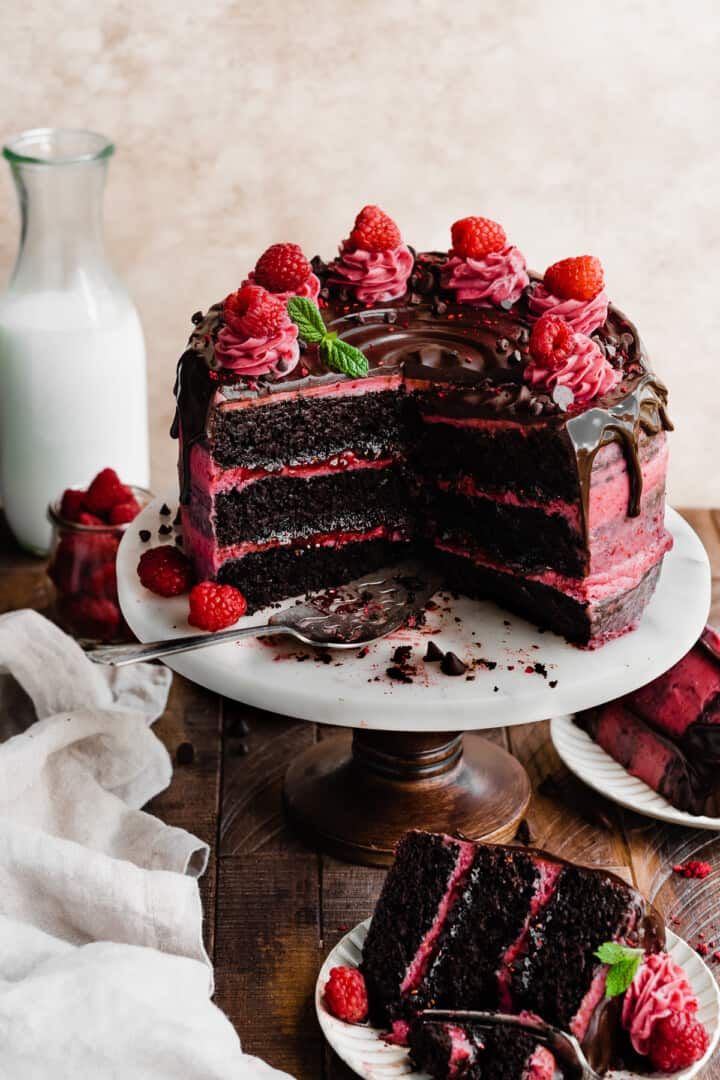 a chocolate cake with raspberries is cut into slices and sits on a plate