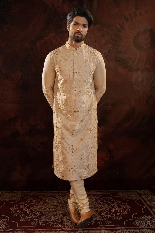 Beige silk kurta with all over hand done french knot embroidery with mustard and maroon highlights. Comes along with churidar.
Components: 2
Pattern: Embroidery
Type Of Work: French Knots
Neckline: Stand Collar
Sleeve Type: Full Sleeves
Fabric: Silk
Color: Beige
Other Details: 
Concealed button placket
Occasion: Sangeet - Aza Fashions Gold Chanderi Kurta With Intricate Embroidery, Gold Chanderi Sherwani With Dabka Work, Gold Semi-stitched Chanderi Sherwani, Gold Embroidered Silk Sherwani, Semi-stitched Kurta With Gold Embroidery For Festivals, Traditional Silk Sherwani With Dabka Work, Traditional Churidar With Gold Embroidery For Designer Wear, Gold Embroidered Jamawar Kurta, Unstitched Traditional Wear With Gold Embroidery For Eid