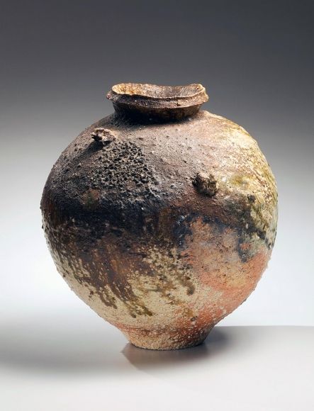 an old, dirty vase is sitting on a white surface with no one around it