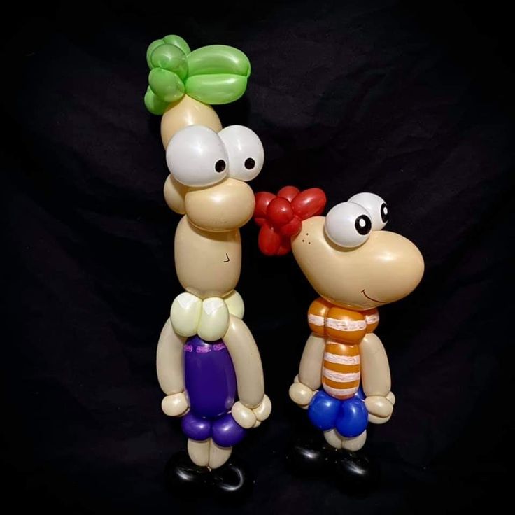 two inflatable balloon figures standing next to each other on a black background,