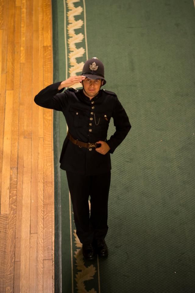 a man in uniform saluting while standing next to a wooden floor with a rug on it