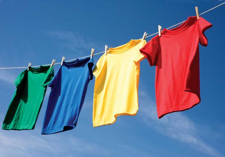 three shirts hanging on a clothes line against a blue sky with clouds in the background