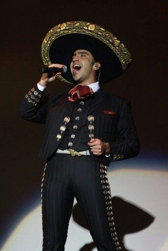 a man wearing a sombrero and singing into a microphone while standing on stage