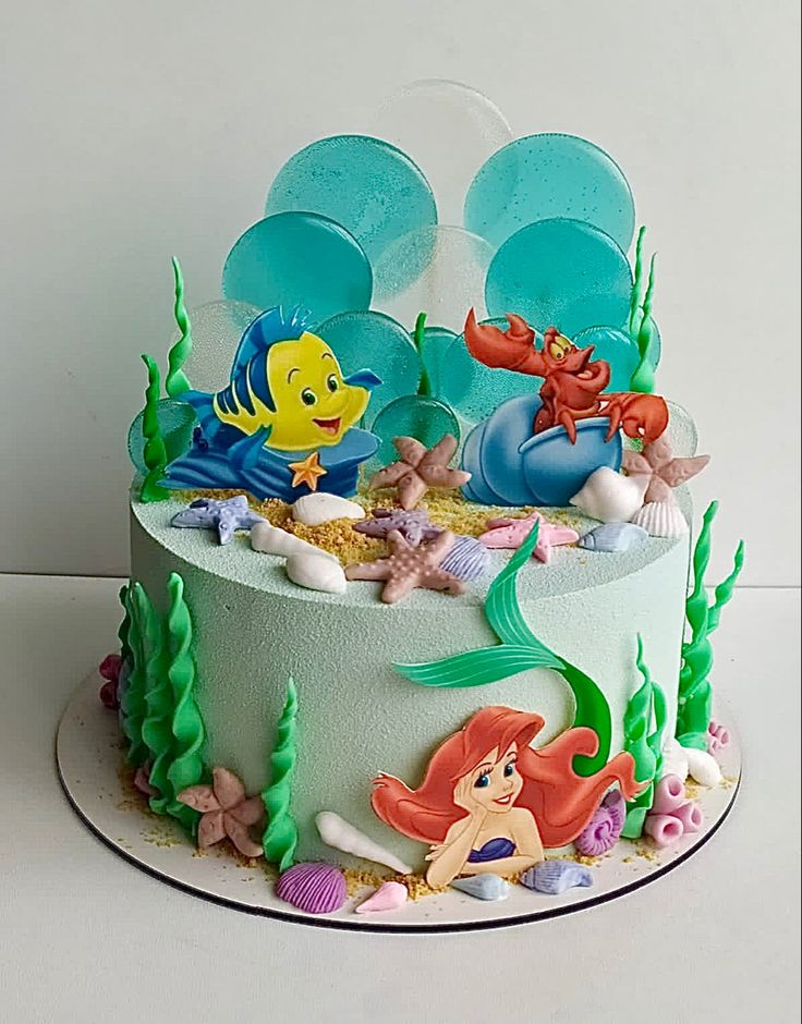 a birthday cake decorated with an ariel the mermaid scene and other disney princess characters on it