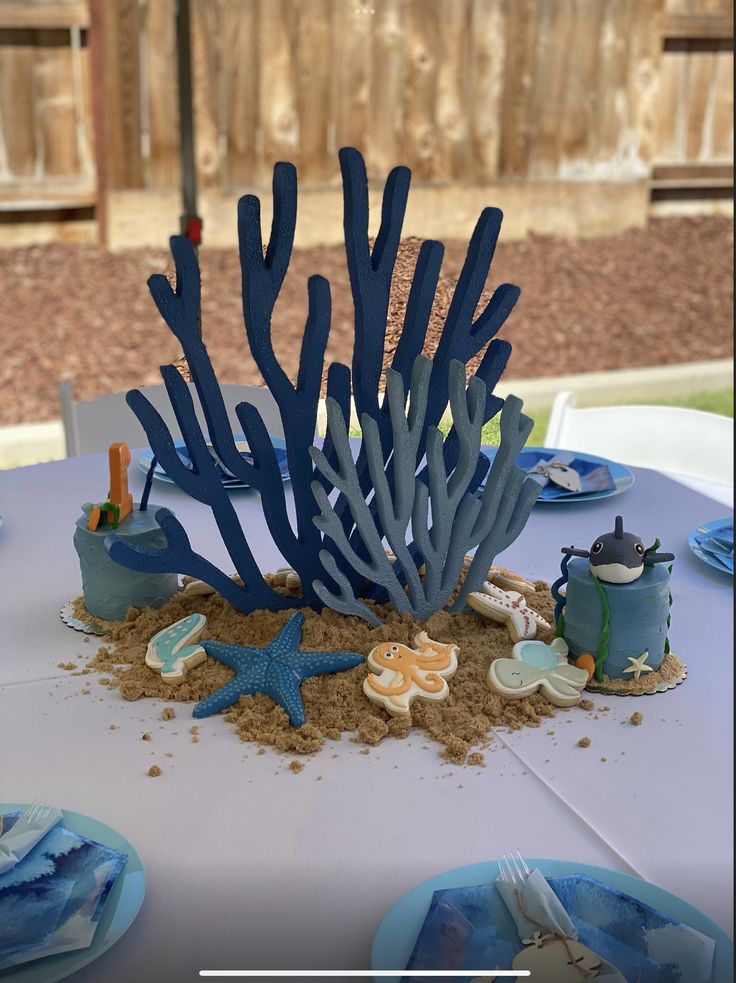 an under the sea themed table setting with blue and white plates, napkins, and utensils