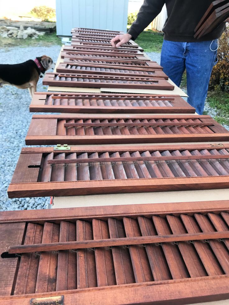 a man standing next to a brown dog on top of a wooden floor covered in slats