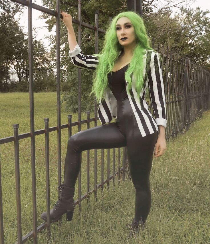 a woman with green hair is leaning on a fence and posing for the camera,