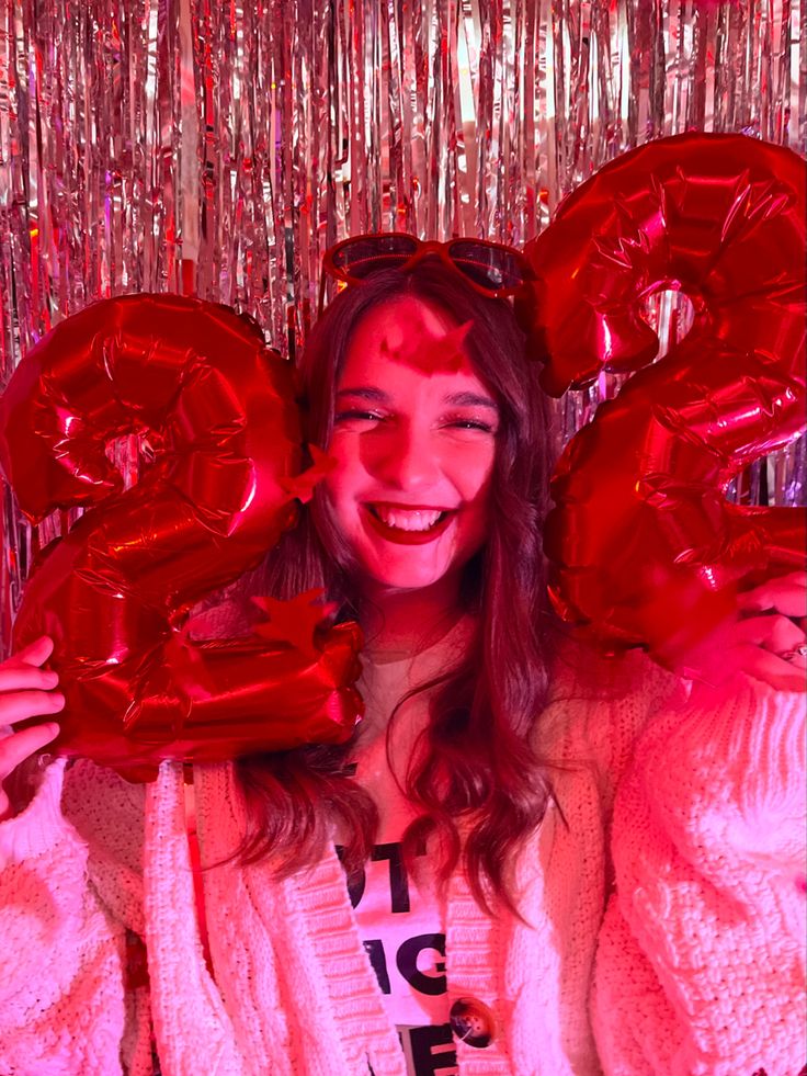 a woman holding two red balloons in front of her face