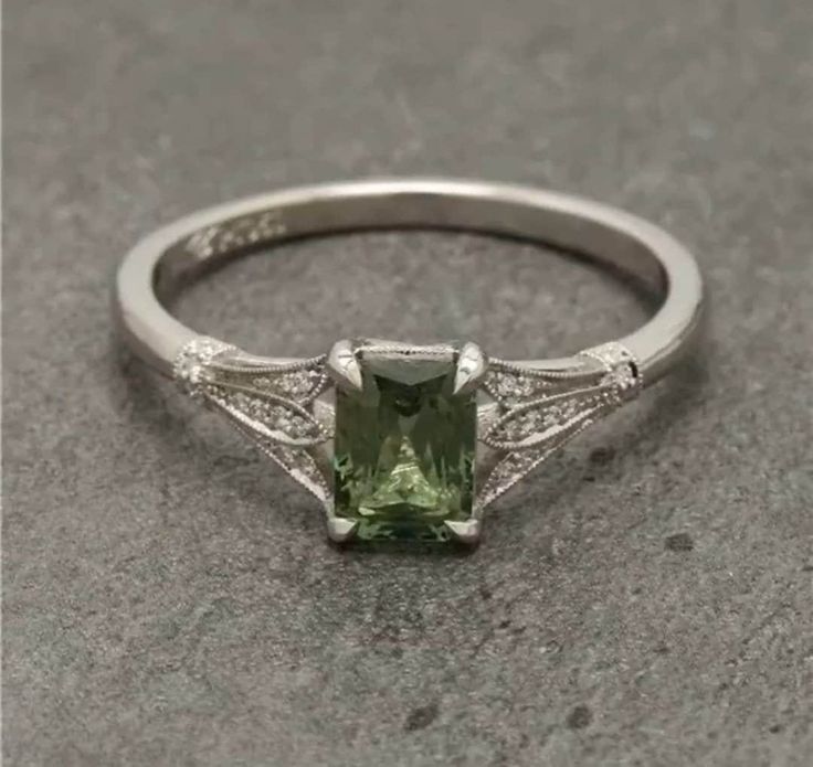 an engagement ring with a green stone in the center