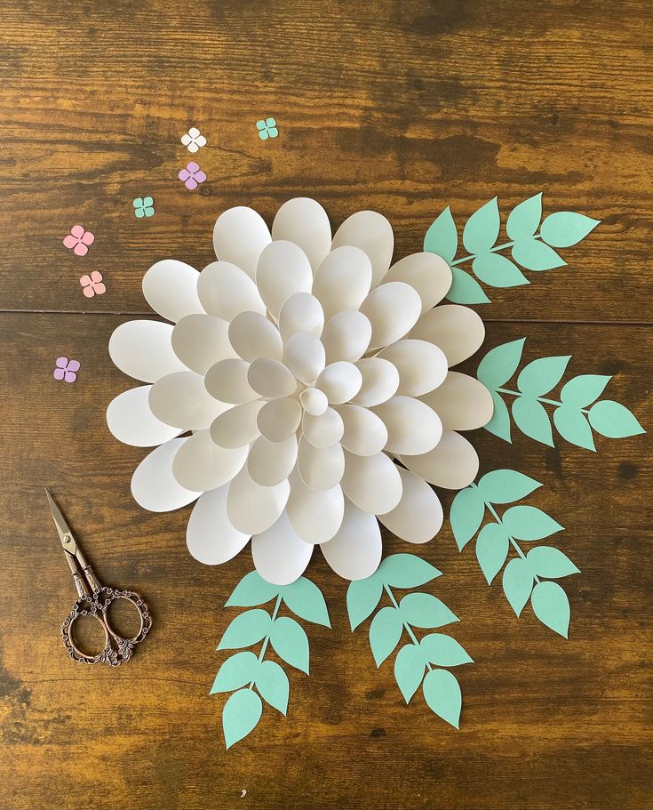 paper flowers and scissors on a wooden table