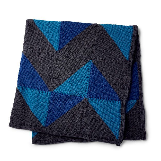 a blue and black blanket on top of a white surface with an image of a triangle in the middle