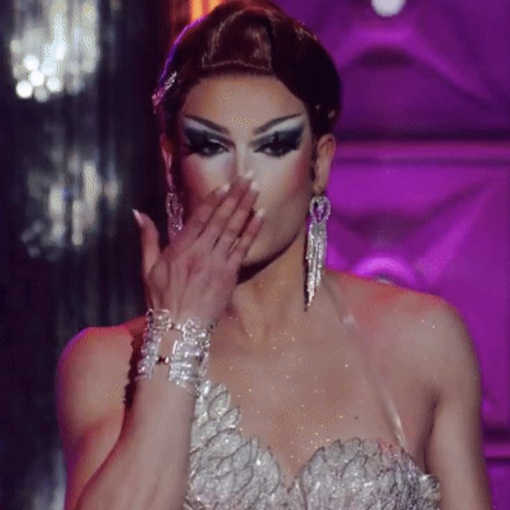 a woman in a white dress holding her hands to her face while standing on stage