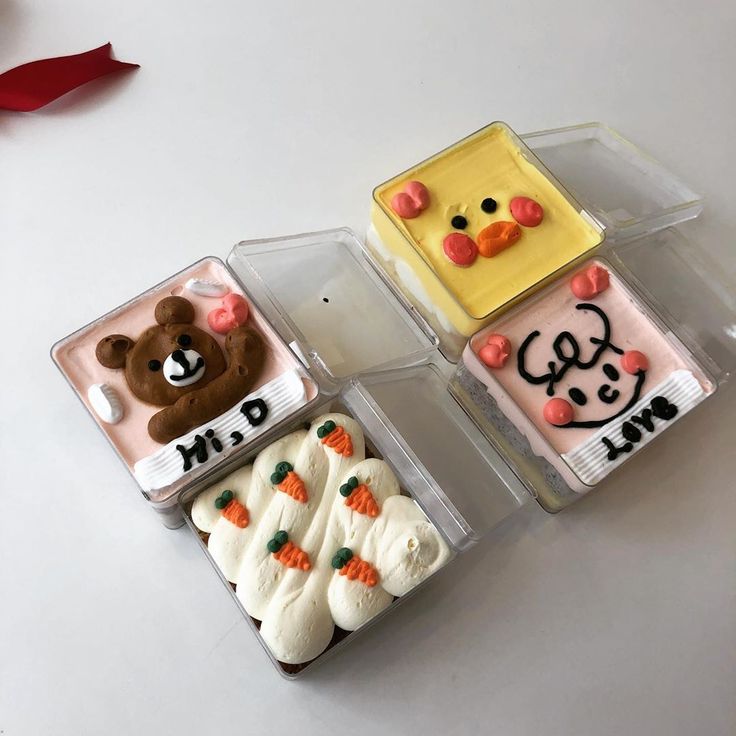 three decorated cookies in plastic containers on a table