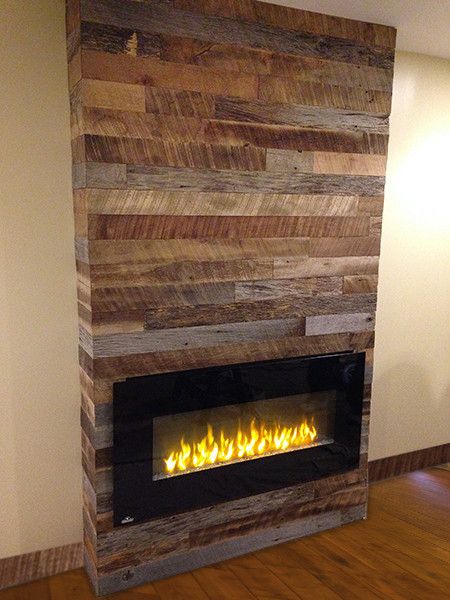 a fire place in the middle of a room with wood paneling on the wall