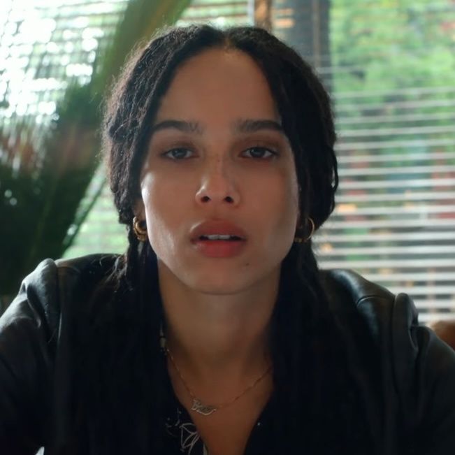 a woman with dreadlocks sitting in front of a window looking at the camera