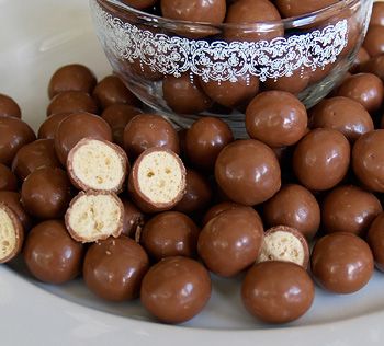 chocolate covered candies are on a plate next to a glass bowl full of them