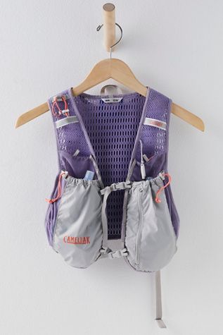 a purple vest hanging on a white wall next to a wooden hanger with clothes