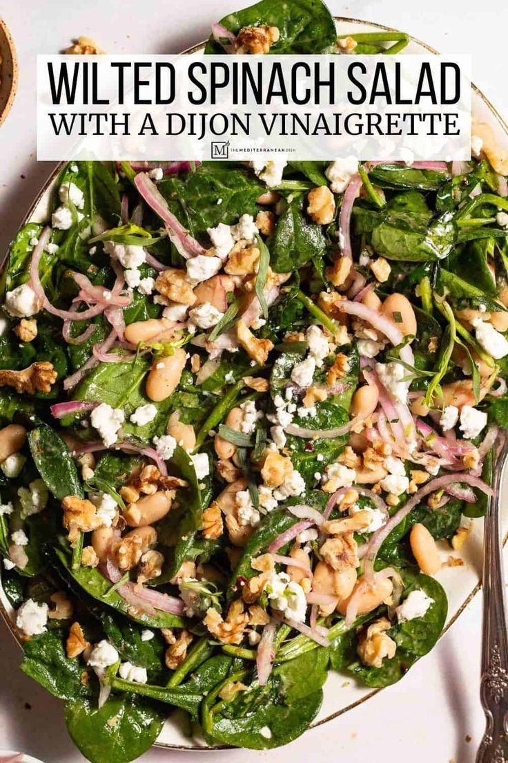 a salad with spinach, feta cheese and red onion on top in a white bowl