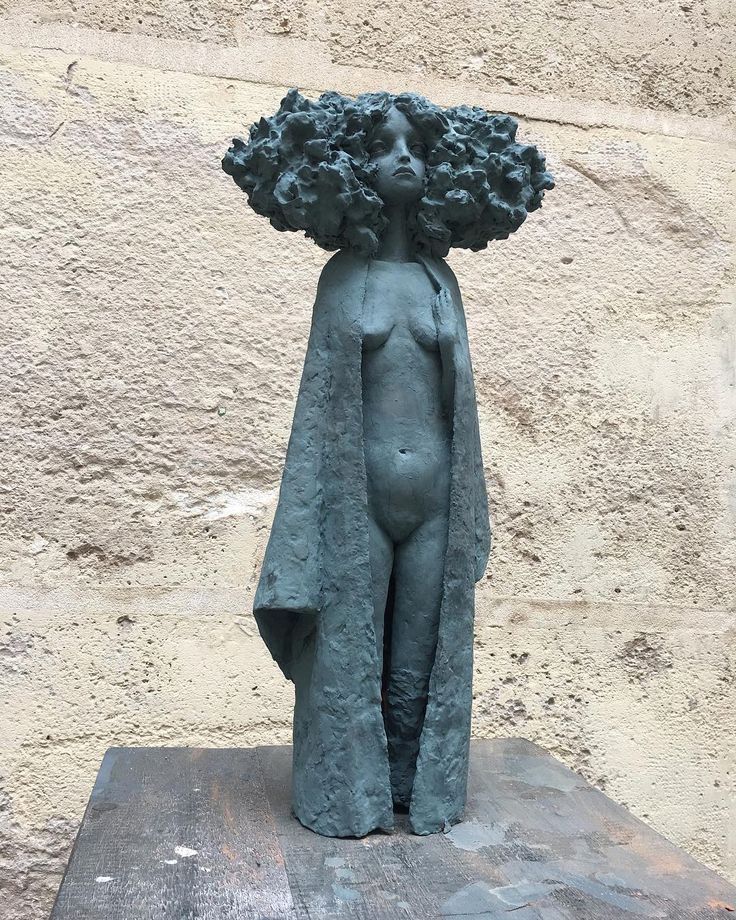 a statue is standing in front of a wall with a flower on it's head