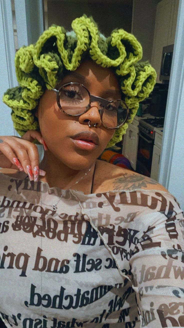 a woman wearing glasses and a green crochet wig with her hands on her shoulder