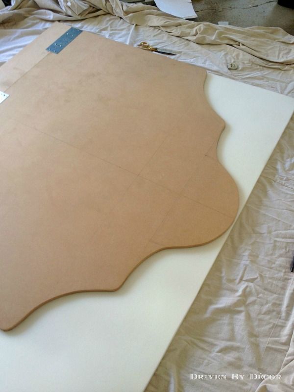 an unfinished piece of plywood sitting on top of a sheet of white paper next to a pair of scissors