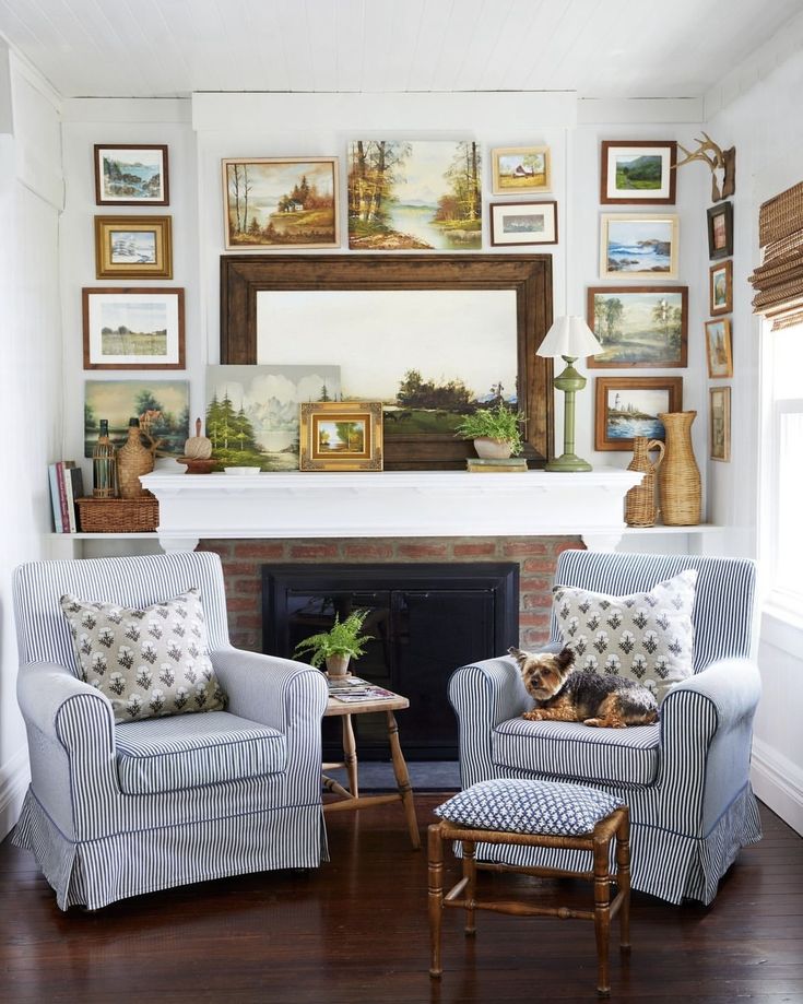 a living room with two chairs and a fire place in front of a painting on the wall