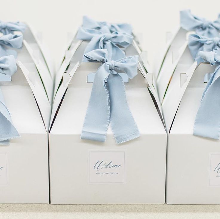 three white boxes with blue bows on them