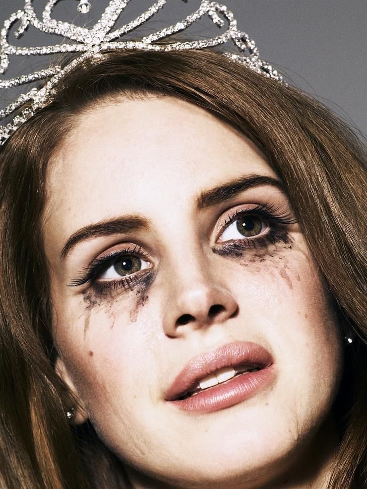 a close up of a person wearing a tiara with makeup on her face and eyeliners