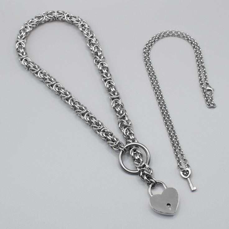 A Heavy Weight, Very Chunky Statement Choker featuring a Functioning Heart shaped Padlock 12mm Width Solid Stainless Steel Chainmail (Byzantine) Chain Chrome Plated Brass Working Heart Shaped Padlock (32mm x 40mm) 32mm Steel O Ring Hand Made in the UK Key supplied as standard on a clip unless Key Holder Chain option is selected (see last image) Optional Key Holder Chain 4.7mm Width Belcher Chain 20 Inch Fixed Length (51cm) Key Size 24mm x 11mm Sizing: Small 15 Inches (38cm) + Lock & O ring Mediu Gothic Silver Choker With Adjustable Chain, Padlock Choker, Adjustable Stainless Steel Chain Choker, Adjustable Gothic Chain Choker, Layering Earrings, Silver Chain Link Punk Necklace, O Ring Choker, Word Necklace, Padlock Necklace