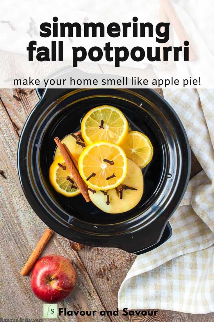 a bowl filled with sliced oranges and cinnamon on top of a wooden table next to an apple