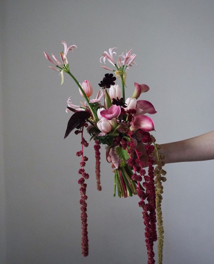 a person holding a bouquet of flowers in their hand with beads hanging from the stems