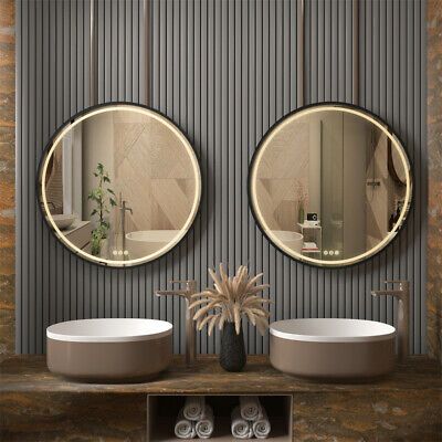 two round mirrors hanging on the side of a wall next to sinks in a bathroom