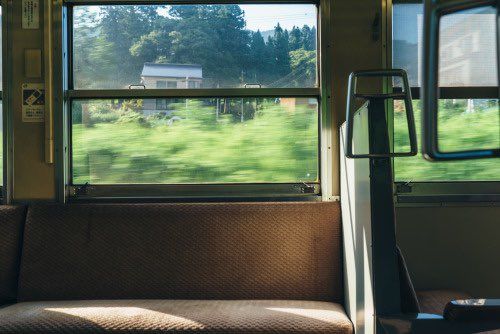 the inside of a train car with windows open and trees in the backround