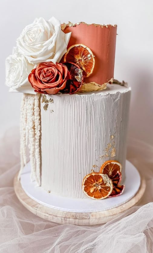 a white cake with oranges and flowers on top