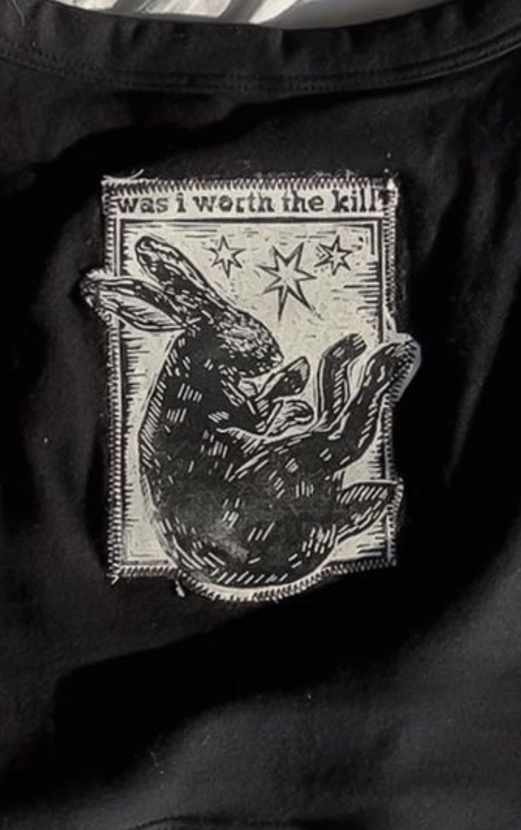 a close up of a black shirt with a rabbit on it's back pocket