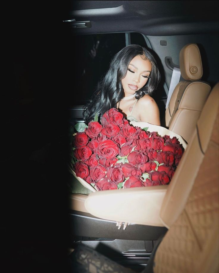 a woman sitting in the back seat of a car with roses wrapped around her body