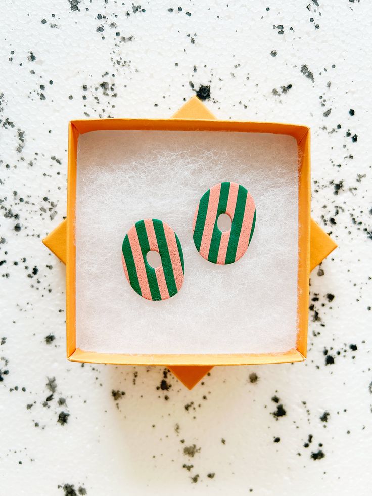 two green and white striped buttons in an orange box on top of black speckles