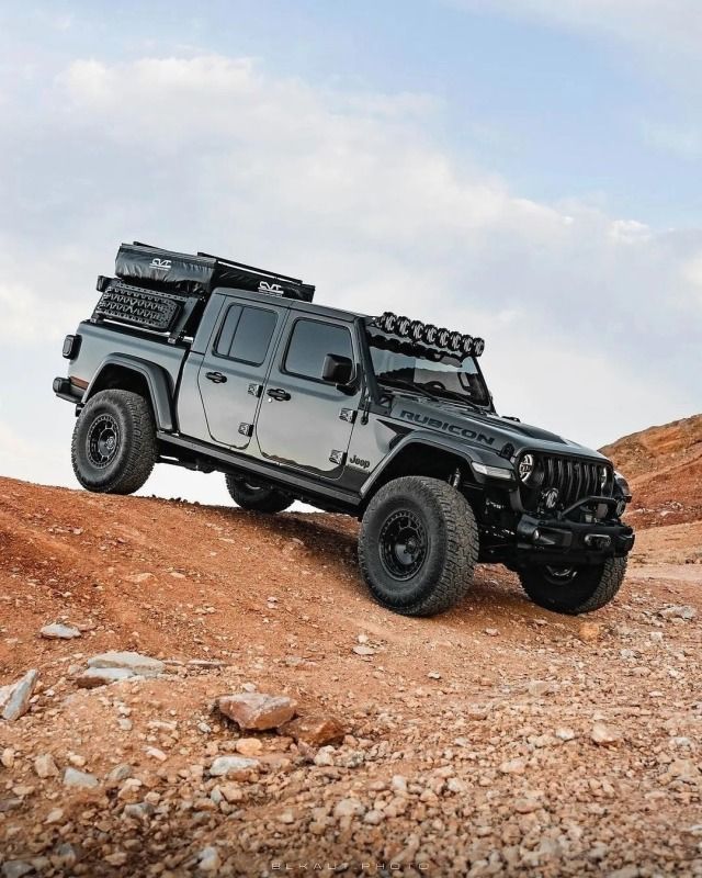 a black jeep is driving down a rocky hill in the desert with no one around it