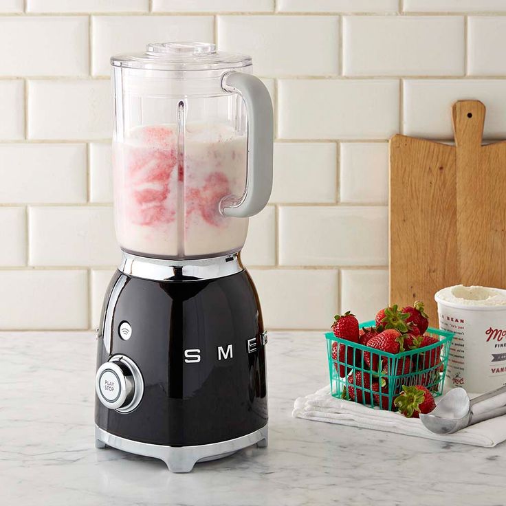 a blender sitting on top of a counter next to a basket of strawberries