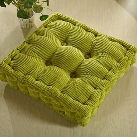 a green cushion sitting on top of a wooden table next to a vase with flowers